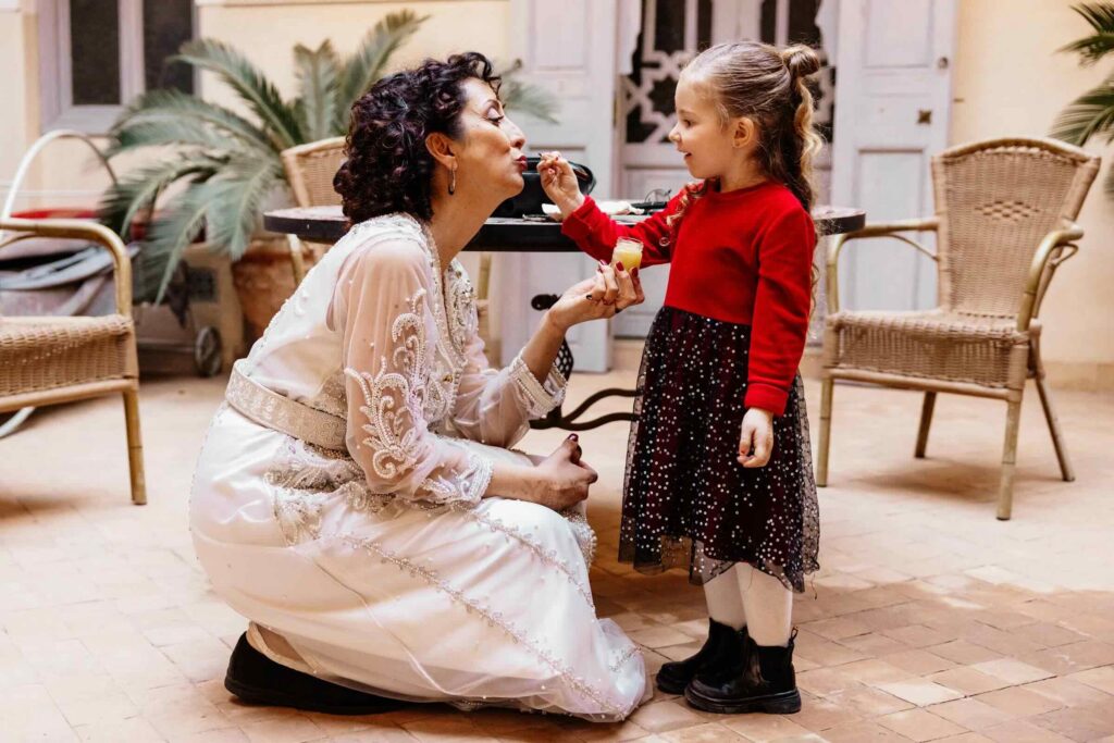 Petite fille maquillant la mariée pendant les préparatifs du mariage à MarrakechYoung girl applying makeup to the bride during wedding preparations in Marrakech